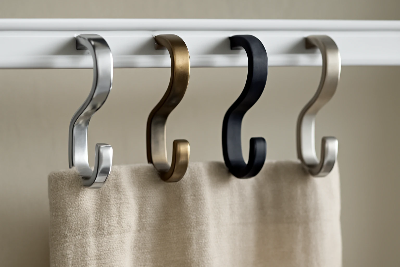 Tight editorial product shot of four curtain hooks clipped into a short section of an overhead curtain track, a narrow swath 
